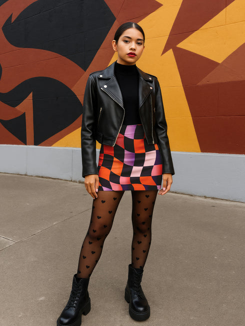 Honey Dazed mini pencil skirt featuring a bold wavy checkerboard pattern in black, orange, purple, and pink. Made from soft eco-polyester with a curve-hugging stretch fit and a flattering high-waist silhouette. The print has a slightly glossy finish, giving it a sleek and modern look. Designed for festival fits, streetwear moments, and retro rave energy. A vivid, sculptural mini skirt that pairs easily with crop tops and confident energy.